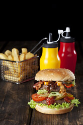 Großer Hamburger mit Pommes frites und Ketchup und Senf in Flaschen - CSF027194