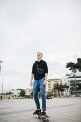 Spanien, Torredembarra, lächelnder junger Mann auf seinem Skateboard - JRFF000436