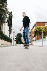 Spanien, Torredembarra, lächelnder junger Mann auf seinem Skateboard - JRFF000442