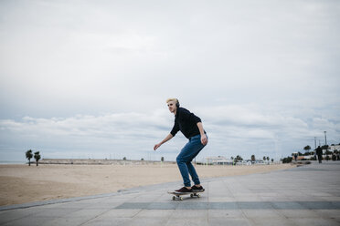 Spanien, Torredembarra, junger Skateboarder, der mit Kopfhörern Musik hört - JRFF000448
