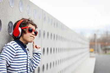 Porträt eines kleinen Jungen, der eine Sonnenbrille trägt und mit Kopfhörern Musik hört - VABF000158