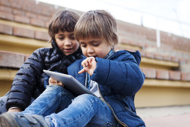 Porträt eines kleinen Jungen, der mit einem digitalen Tablet spielt, während sein Bruder zusieht - VABF000161