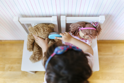 Little girl playing with her teddy and doll, seen from above stock photo