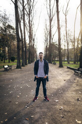 Young man standing in the park with hands in his pockets - MGOF001448