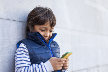 Porträt eines Jungen, der an der Wand lehnt und auf sein Smartphone schaut - VABF000162