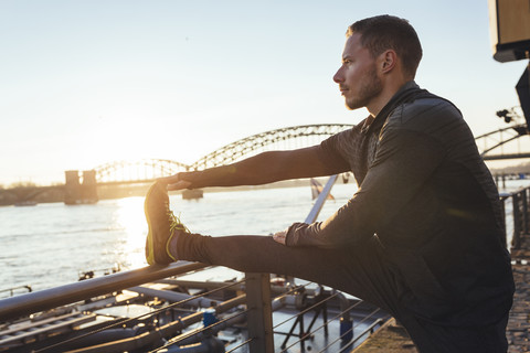 Germany, Cologne, Young man worming up for workout stock photo