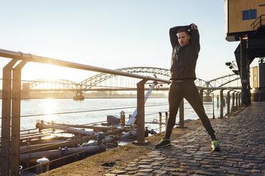 Germany, Cologne, Young man warming up for workout - MADF000801