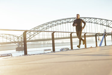 Germany, Cologne, Young man running at the riverside - MADF000806