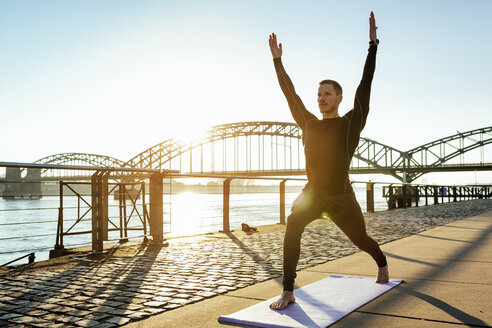 Deutschland, Köln, Junger Mann übt Yoga am Flussufer - MADF000811