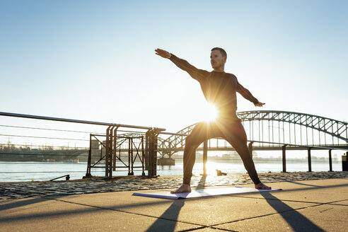 Deutschland, Köln, Junger Mann übt Yoga am Flussufer - MADF000812