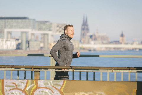 Deutschland, Köln, Junger Mann läuft am Flussufer, lizenzfreies Stockfoto