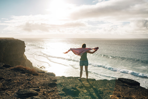 Spanien, Fuerteventura, El Cotillo, Rückenansicht einer Frau mit Blick aufs Meer, lizenzfreies Stockfoto