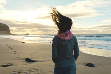 Spain, Fuerteventura, El Cotillo, back view of woman on the beach with blowing hair - GEMF000733