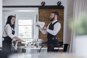 Kellnerin und Kellner polieren Weingläser und Besteck im Restaurant - ZEF008544