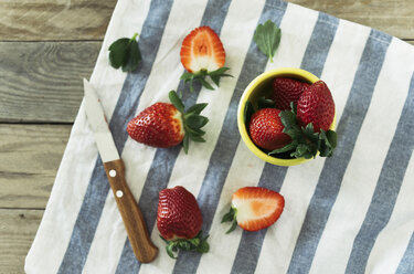 Whole and sliced strawberries and a kitchen knife on striped cloth - JPF000113
