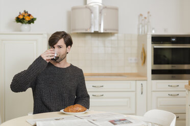 Mann sitzt am Frühstückstisch in der Küche und trinkt Kaffee - SHKF000495