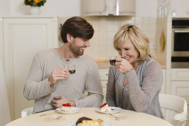 Mutter und erwachsener Sohn trinken Espresso in der Küche und haben Spaß zusammen - SHKF000497