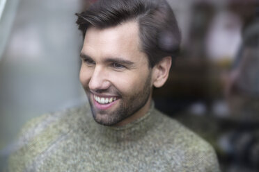 Portrait of smiling man looking through windowpane - SHKF000501