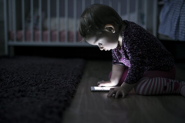 Kleinkind sitzt auf dem Boden und spielt mit Smartphone - HAPF000236