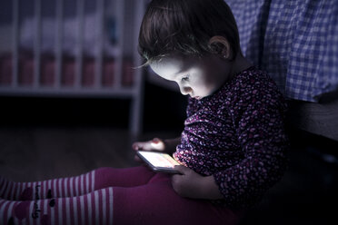Kleinkind sitzt auf dem Boden und spielt mit Smartphone - HAPF000237