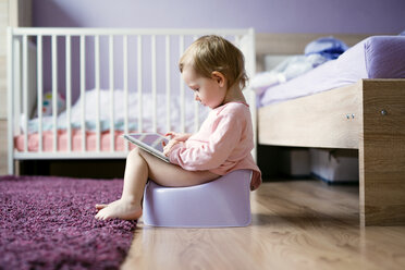 Kleinkind auf dem Töpfchen sitzend und mit digitalem Tablet spielend - HAPF000239