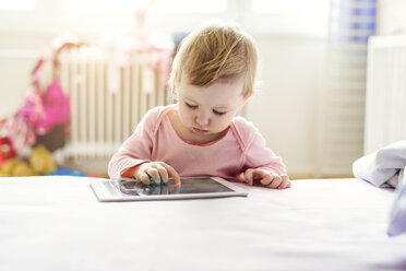 Kleinkind spielt mit digitalem Tablet auf dem Bett - HAPF000241