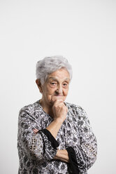 Portrait of smiling senior woman with hand on her chin in front of white background - RAEF000898