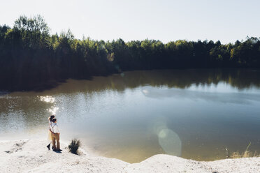 Lovers standing arm in arm at water's edge - MJF001710