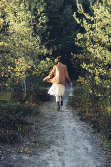 Back view of old-fashioned styled woman with storm lamp walking on a path - MJF001724