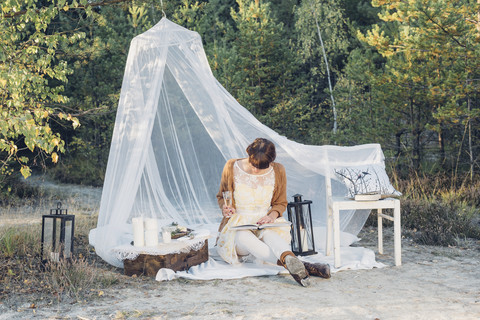 Frau liest ein Buch in einem romantischen Lager in herbstlicher Natur, lizenzfreies Stockfoto