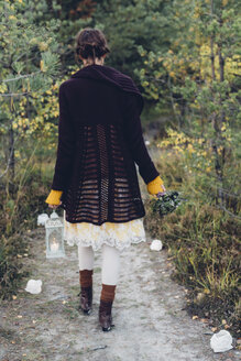 Back view of old-fashioned styled woman with storm lamp walking on a path - MJF001735