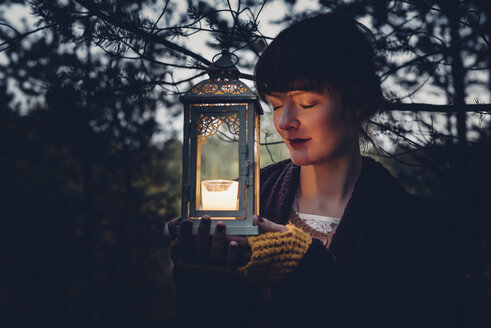 Portrait of woman with closed eyes holding storm lamp, - MJF001738