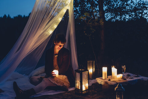 Happy woman in a romantic camp in autumnal nature by candle light - MJF001739