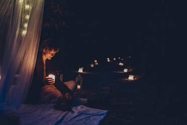 Frau in einem romantischen Lager bei Kerzenlicht in der Natur - MJF001740