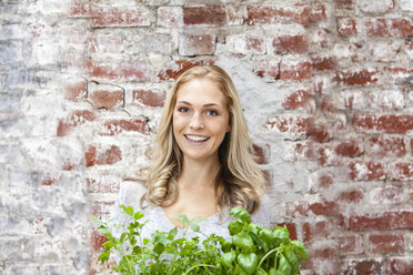 Portait of smiling blond woman with herbs - FMKF002282