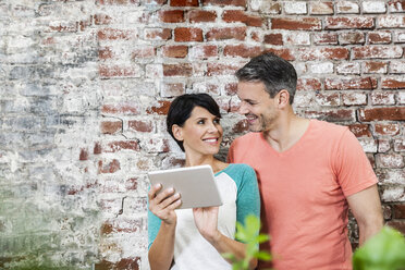 Smiling couple sharing digital tablet - FMKF002327