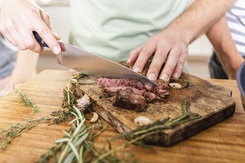 Schneiden eines Steaks auf einem Schneidebrett - FMKF002336