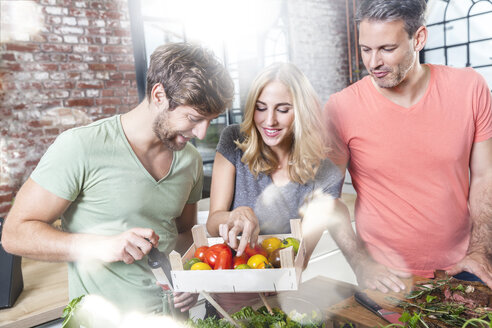 Freunde in der Küche betrachten eine Kiste mit Tomaten - FMKF002341