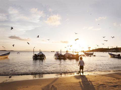 Venezuela, Isla Margarita, Juan Griego, Rückenansicht eines kleinen Jungen, der bei Sonnenuntergang am Meer steht, lizenzfreies Stockfoto