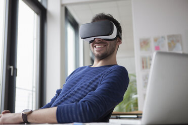 Lächelnder Mann mit Virtual-Reality-Brille im Büro - RBF004087