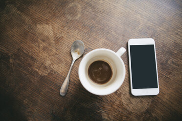 Kaffeetasse mit Resten von Kaffee, Löffel und Smartphone auf Holz - EBSF001233