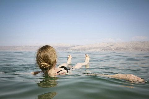 Israel, Frau schwimmt auf dem Wasser des Toten Meeres, lizenzfreies Stockfoto