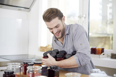 Young man with jam jars in kitchen - FMKF002345