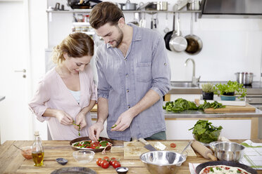 Couple preparing pizza in kitchen - FMKF002346
