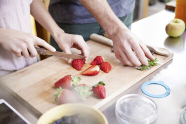 Couple cutting strawberries in kitchen - FMKF002348