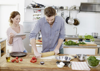 Couple preparing pizza dough in kitchen - FMKF002355