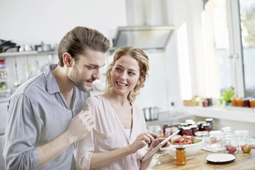 Ehepaar schaut in der Küche auf ein digitales Tablet - FMKF002361
