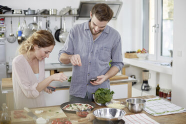 Couple preparing pizza in kitchen - FMKF002377