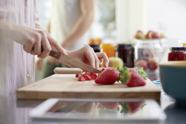 Frau schneidet Erdbeeren in der Küche - FMKF002382