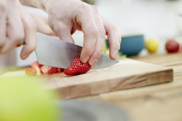 Mann schneidet Erdbeeren in der Küche - FMKF002387
